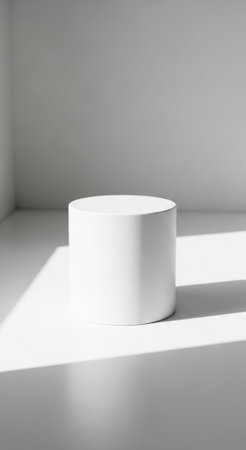 Simple white cylindrical product display stand positioned in a bright minimalist room, illuminated...