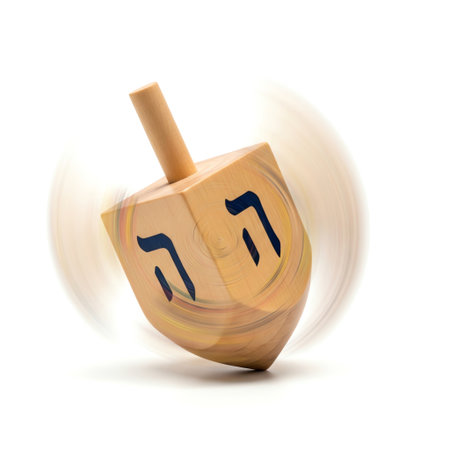 Wooden dreidel spinning with traditional hebrew letters; chanukah game toy on white surfaceの写真素材