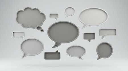 Different types of blank speech bubbles, including thought clouds, in shades of gray on a light studio backgroundの写真素材