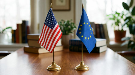Flags of USA and EU on golden stands on a shiny wooden table in a room with blurred background of...