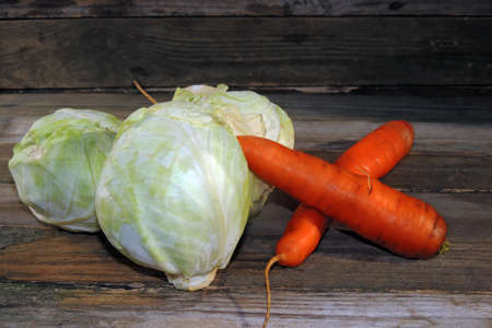 CABBAGE AND CARROTS ON A WOODEN BACKGROUNDの写真素材