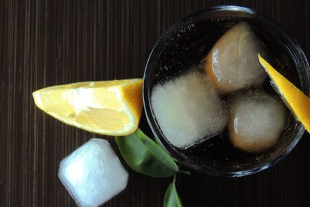 Cocktail with cola and ice on wooden table. in a glass with a cocktail, put a slice of lime