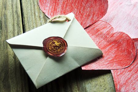 Valentine's day.Envelope with  red hearts on Brown wooden background.