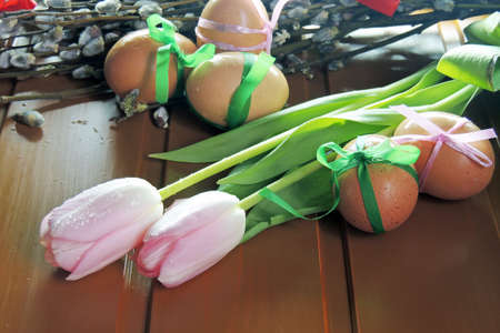 Easter eggs, tulips and blank greeting card over blue wooden table. Top view with copy spaceの写真素材