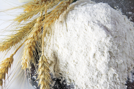 Heap of wheat flour with spikelets isolated on whiteの写真素材