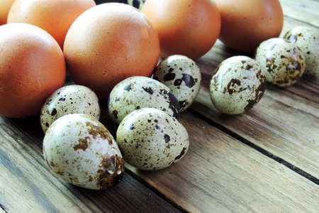 A goose egg, hen egg and a quail egg  on a wooden background