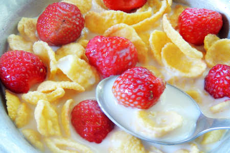 Cornflakes cereal and strawberry bowl for breakfast on blue bowlの写真素材