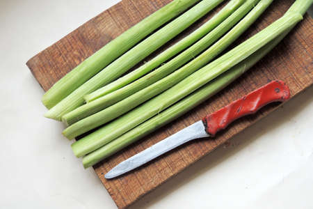 rhubarb stalks with leaves, freshly picked from the garden on a wooden table, closeup with selected focus, narrow depth of fieldの写真素材