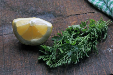sliced lemon and green herbs on a wooden backgroundの写真素材