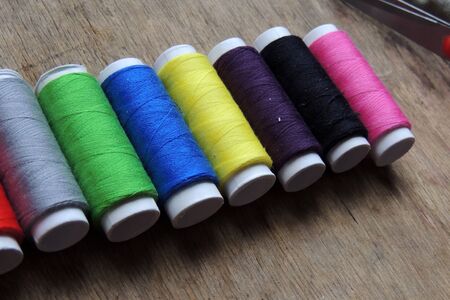 Colored thread and scissors on wooden background. Background