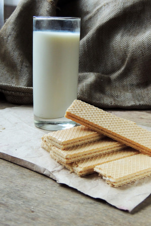 A glass of cold Milk and waffles on wooden backgroundの写真素材