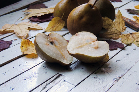 Pear and autumn leaves on wood table closeupの写真素材