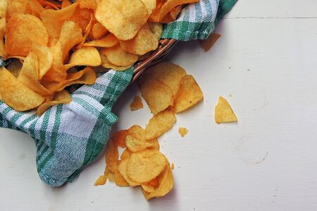 Potato chips in bowl and fresh potatoの写真素材