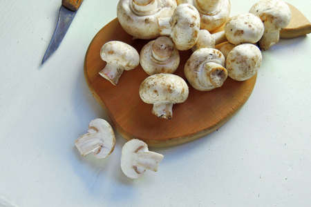 Fresh organic champignon mushrooms on chopping board with knifeの写真素材