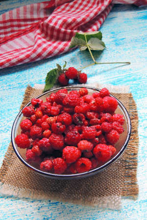 Ripe sweet raspberries in bowl on wooden table. Close up, top view, high resolution product