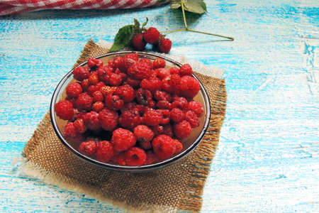 Ripe sweet raspberries in bowl on wooden table. Close up, top view, high resolution product