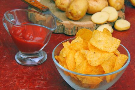 Potato chips on old paper with tomato sauce. On black rustic background.の写真素材