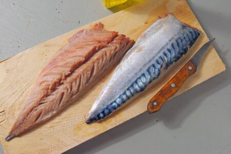 Fresh fish. Mackerel with salt, lemon and spices on gray background. Cooking fish with herbs. Top...