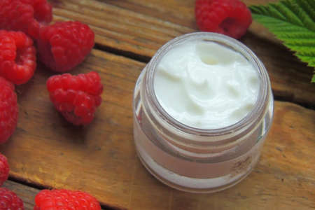 Diy raspberry mask in a small white bowl, cosmetic brush and cotton pads. Homemade beauty treatment...