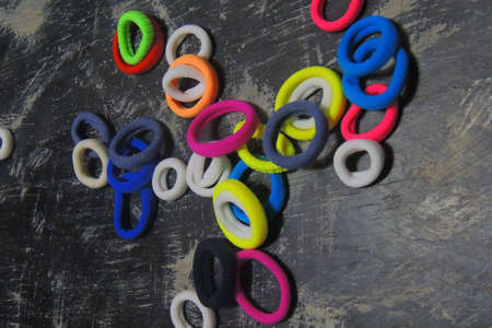 many round, small, colorful hair ties against a black background