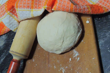 Dough with rolling pin and flour on a stone surface