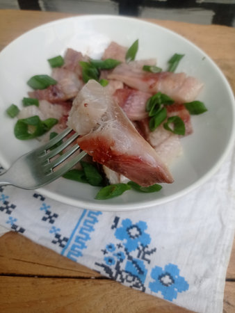 Slices of raw fish with herbs on a white plate.の写真素材