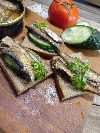 Sandwiches with sprats and vegetables on a wooden board.の写真素材
