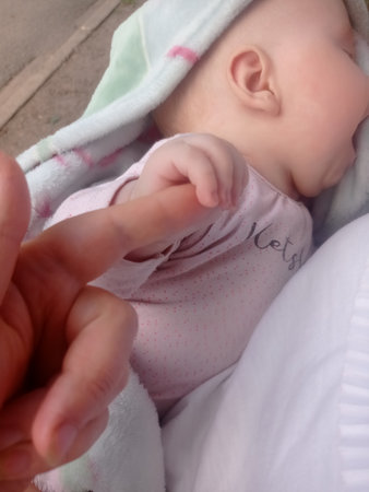 Mother's hand holding the finger of her newborn baby in the parkの写真素材