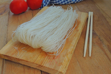 Rice noodle for cooking and chopsticks on wood background.の写真素材