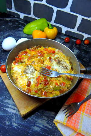 Fried eggs with vegetables in a frying pan on a dark backgroundの写真素材