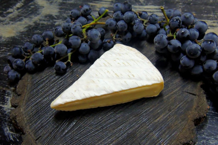 Camembert cheese and black grapes on black wooden background. Top view.の写真素材