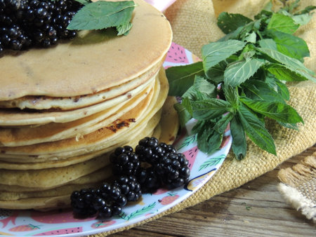 Pancakes with blackberries and mint on a wooden table.の写真素材