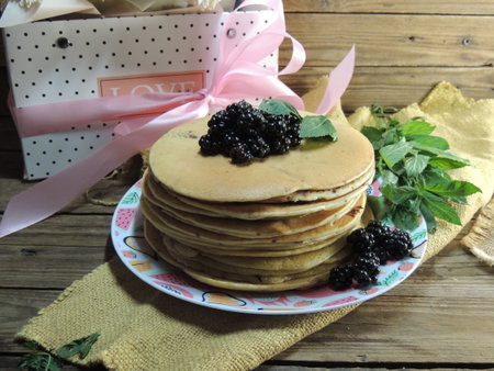 Stack of pancakes with blackberries and mint on a wooden background.の写真素材