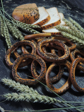 Bread with poppy seeds and wheat ears on a black background.