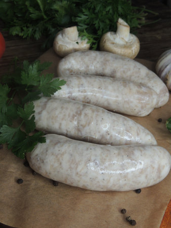 Raw white sausages with herbs and spices on a wooden boardの写真素材