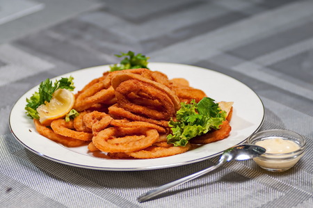 eep batter fried squid rings calamari with green salad on white plateの写真素材