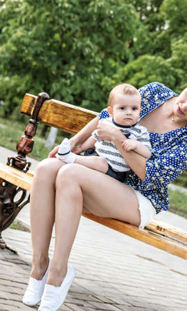Young mather with a little son sitting on her knees on a benchの写真素材