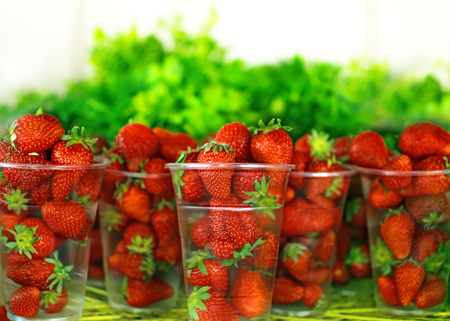 Red fresh strawberry berries in transparent plastic glasses for sale on village market at summer day. Healthy diet foodの写真素材