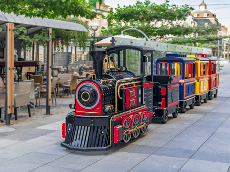 Childrens summer attraction locomotive with cars on a city street