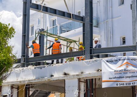 CYPRUS, Kyrenia - JUNE 10, 2019: Builders are building a new building on the roof. Workers dressed...