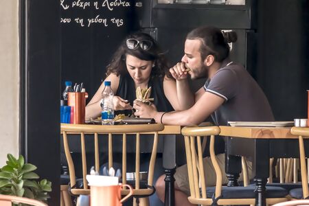 CYPRUS, NICOSIA - JUNE 10, 2019: Young couple eating in street outdoor restaurant. Man and woman enjoying fast foodのeditorial素材