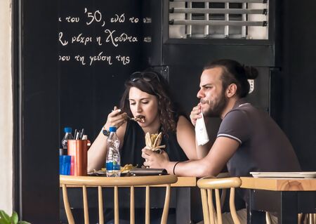 CYPRUS, NICOSIA - JUNE 10, 2019: Young couple eating in street outdoor restaurant. People enjoying fast food in cafeのeditorial素材