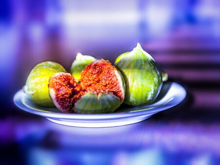 Fresh ripe figs on a plate on bright purple neon background.の写真素材