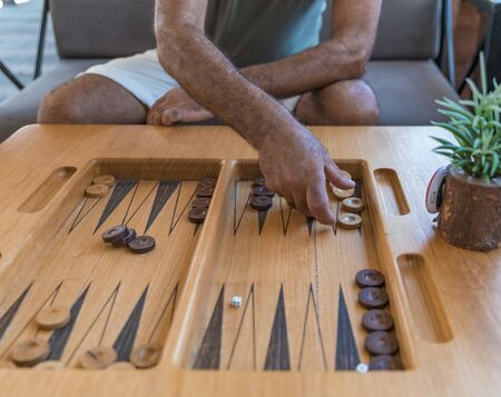 Male playing a traditional oriental board game of backgammon. Mens hands moving chips