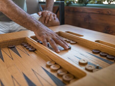 Male playing a traditional oriental board game of backgammon. Mens hands moving chips