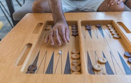 Male playing a traditional oriental board game of backgammon. Close-up mens hands throwing dice