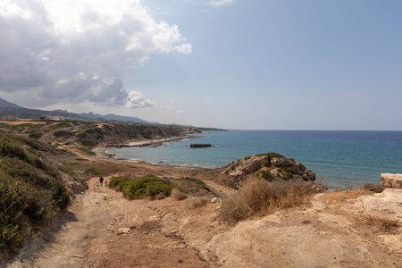 Mediterranean Sea in Northern Cyprus. The ruins of an ancient building on the island. Summer seashore with transparent blue water. Seascape. Skyline with clouds.の写真素材