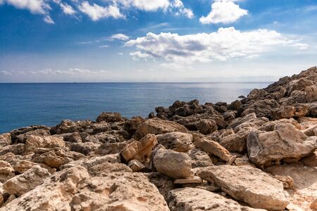Mediterranean Sea in Northern Cyprus. Summer rocky coast, transparent calm blue water and white clouds on blue sky. Seascape. Skylineの写真素材
