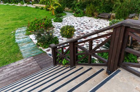 Beautiful garden landscape with exotic green and flowering plants and garden wood decor. Steps with...