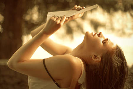 Retro style profile portrait of a young beautiful sad woman reading a letter in a summer garden.